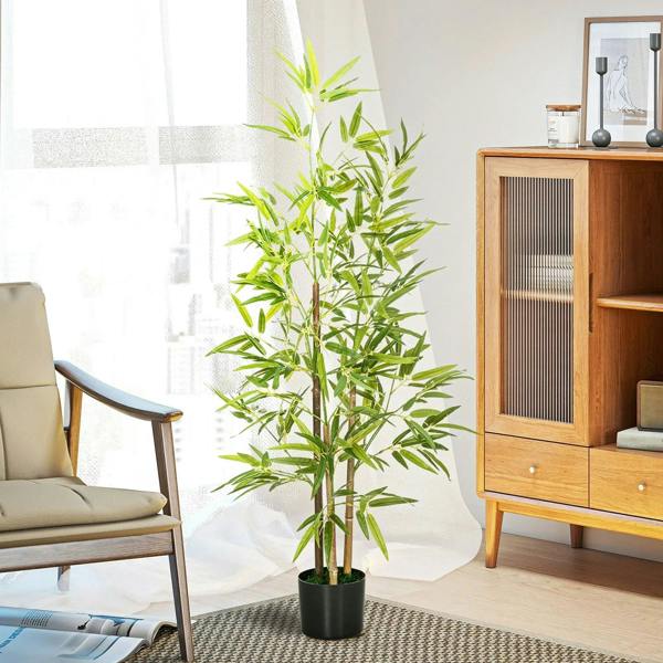 Artificial bamboo plant with green leaves in a black pot in a bright living space