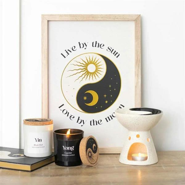 Ceramic yin-yang oil burner with speckled white body, black dish, and tealight flame