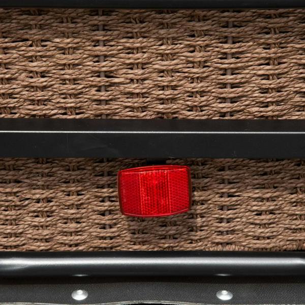 Red reflector on wicker cargo panel of black bicycle trailer