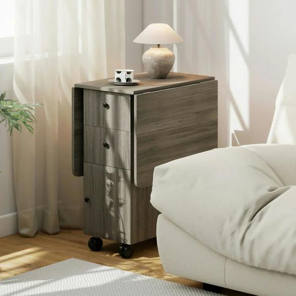 Grey drop-leaf dining table with side drawers and casters beside a sofa