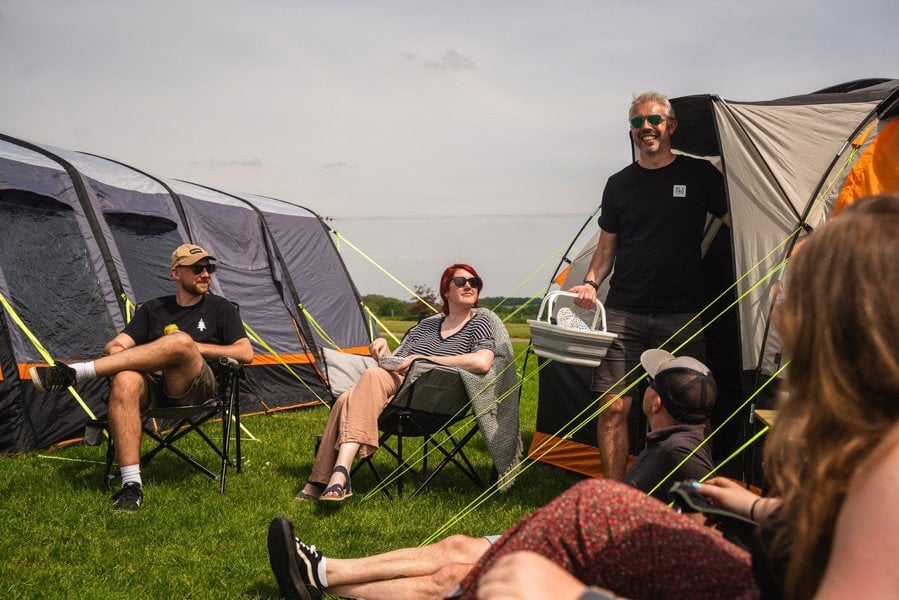 A small gathering of friends takes place between an OLPRO Wichenford 8.0 poled tent & Blakedown inflatable tent at a festival.