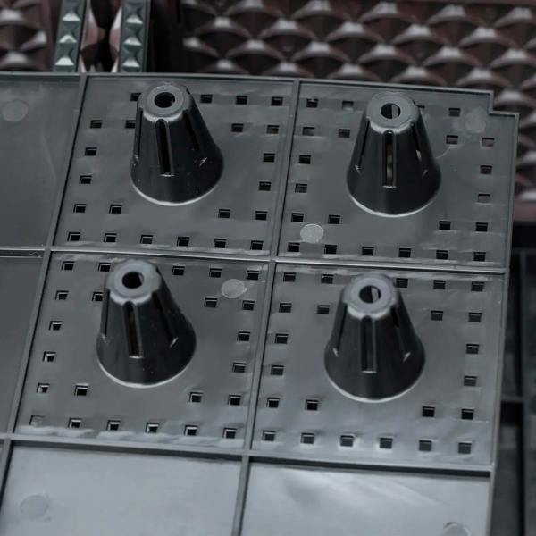 Close-up of raised planter base insert with drainage holes and water outlets