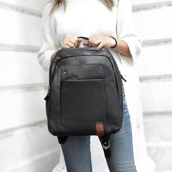 Person holding a black backpack against a white background