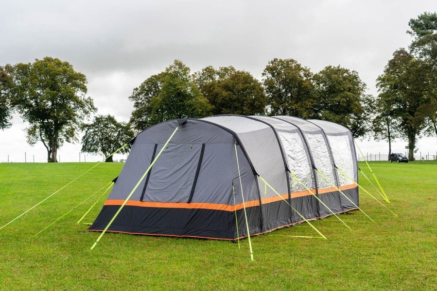 An image of the OLPRO Blakedown Breeze 4 Berth Inflatable Tent pitched on a campsite with a treeline in the background.