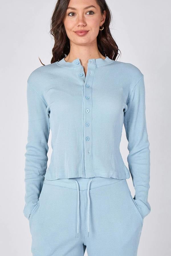 Woman wearing a light blue button-up shirt and pants on a white background