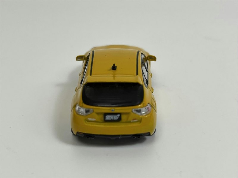 a yellow toy car on a white surface