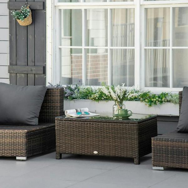 Brown PE rattan coffee table with clear glass top in modern patio setting.