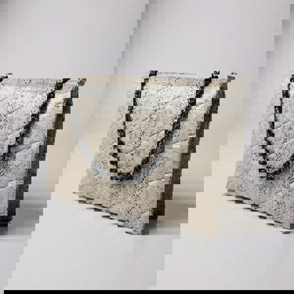 Quilted clutch bag with snake print and black chain strap on a light gray background