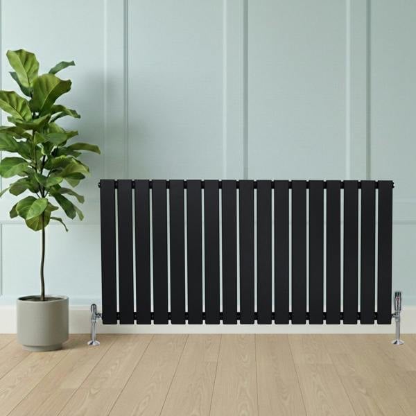 Flat black single column radiator with sleek vertical slats, paired with chrome valves, set against a light wall and wooden floor