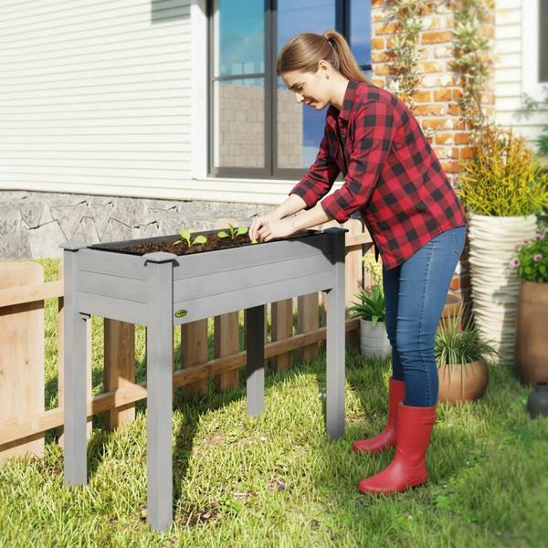 Dark grey raised planter box while someone plants inside the open bed.