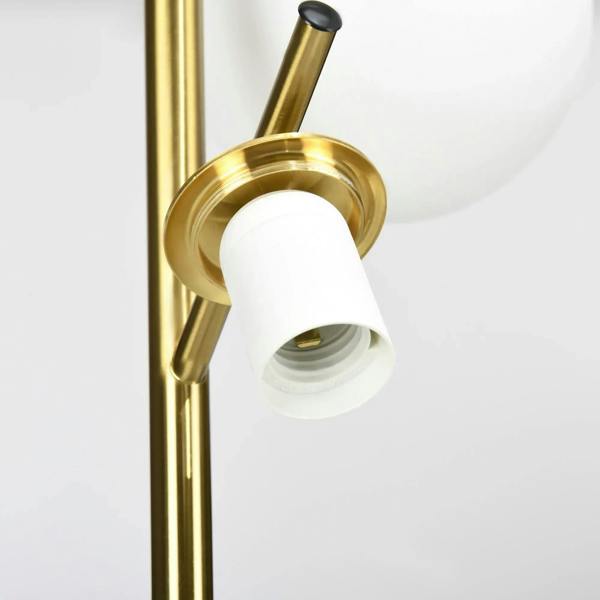 Three-light floor lamp socket with white globe bulb shades on gold metal frame