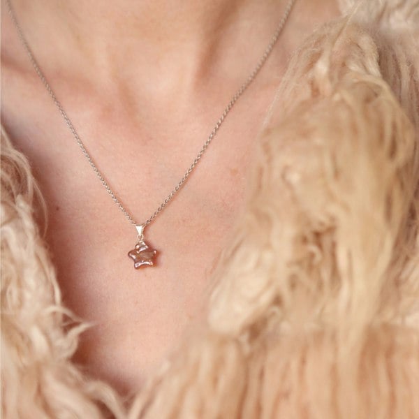 A woman wearing pearl star pendant charm on silver chain.