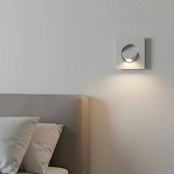White recessed LED reading light for bed mounted on the wall next to a bed in a modern bedroom
