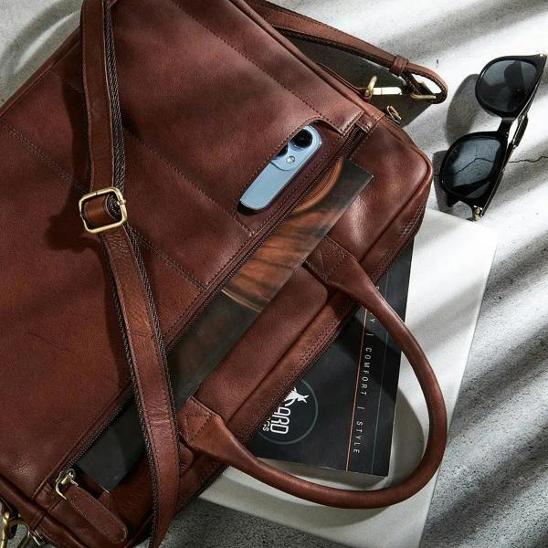 Brown leather bag with phone, sunglasses, and card on a light surface