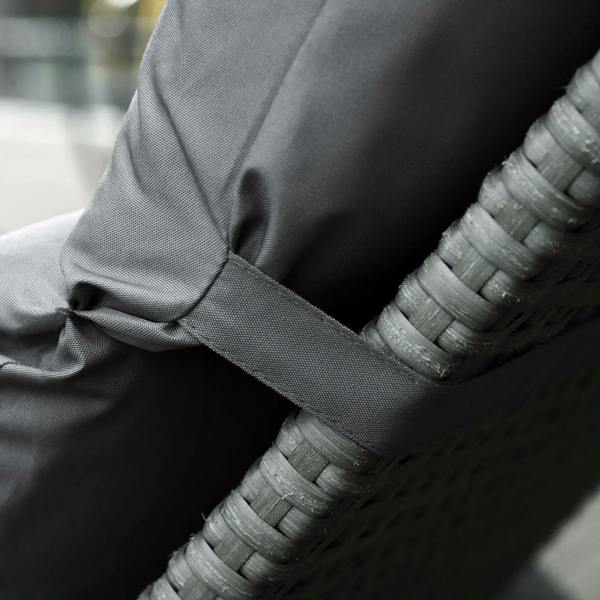 Dark grey cushion strap tied to woven rattan edge, securing seat cushion in place
