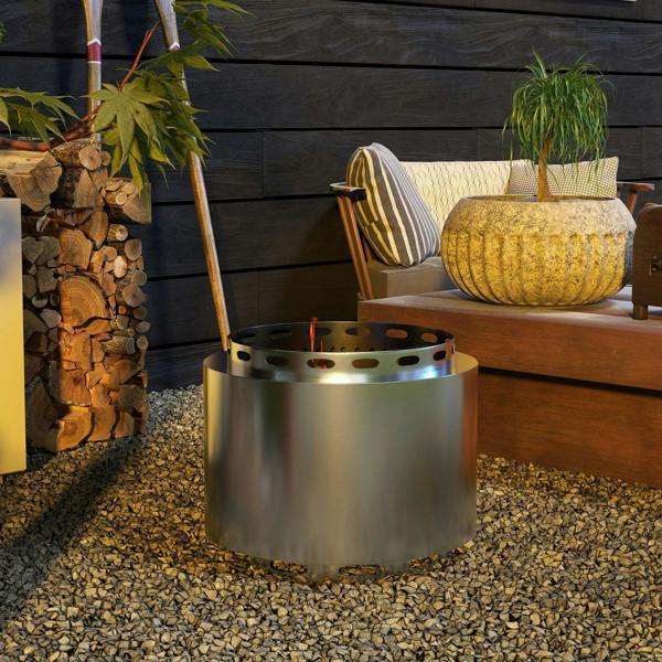 Stainless steel fire pit on gravel with vented top ring and burning flames