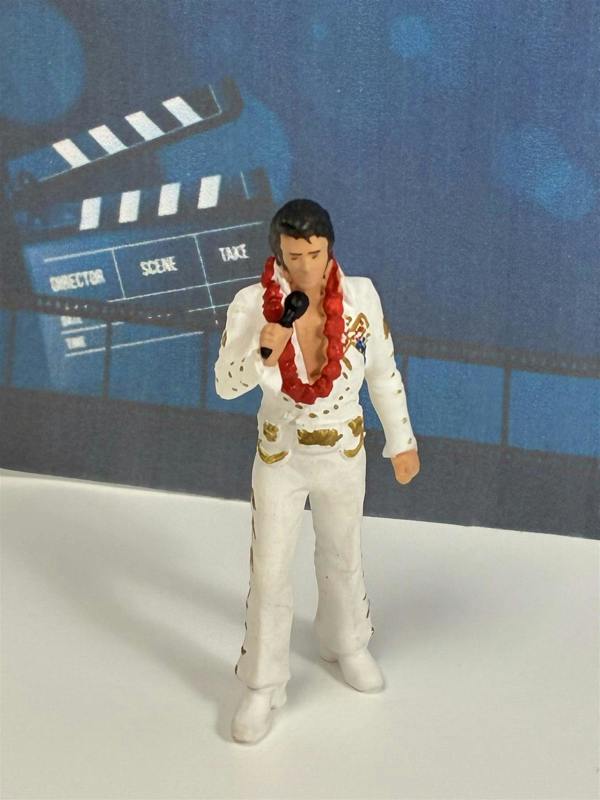 a toy figurine of a man in a white suit with a microphone