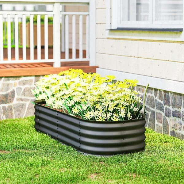 Dark grey galvanized metal raised planter bed with yellow flowering plants in grass