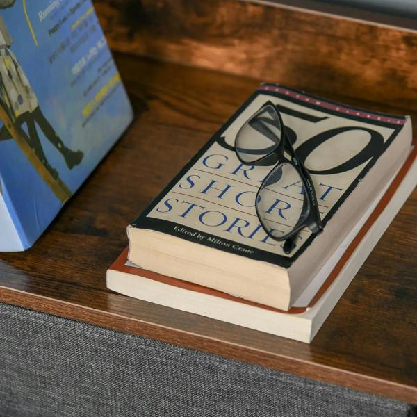 Books displayed on open shelf of a black cabinet with gray fabric drawer front