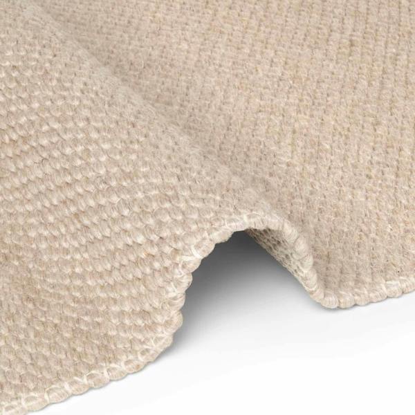 Close-up of a beige textured rug corner on a white background