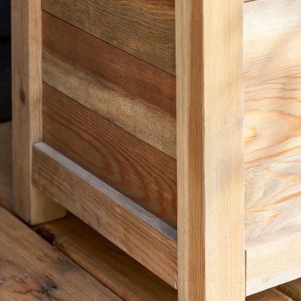 A close-up detail of the sturdy corner post, ground-clearance leg, and natural timber grain panels of the Natural Spruce Trough Planter by Abode Home & Gifts.