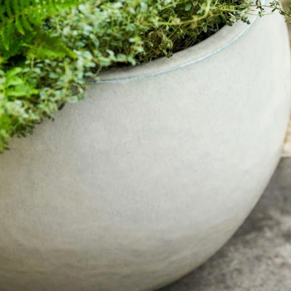 A close-up detail shot showing the textured white speckled reactive glaze and curved rim of the Bourton 42cm white glazed terracotta planter with trailing green herbs.