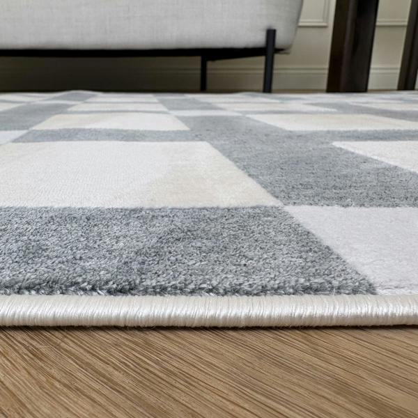 Checkered area rug with gray and white squares on a wooden floor.