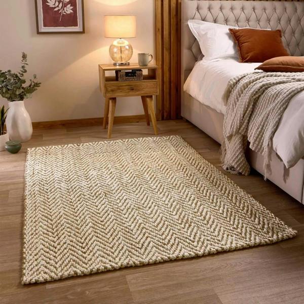 Bedroom with a patterned rug, bed, and side table.