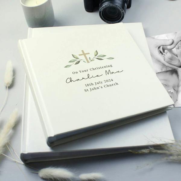 A white square personalised photo album displaying custom engraved silver text details for a Christening event, isolated on a white background.