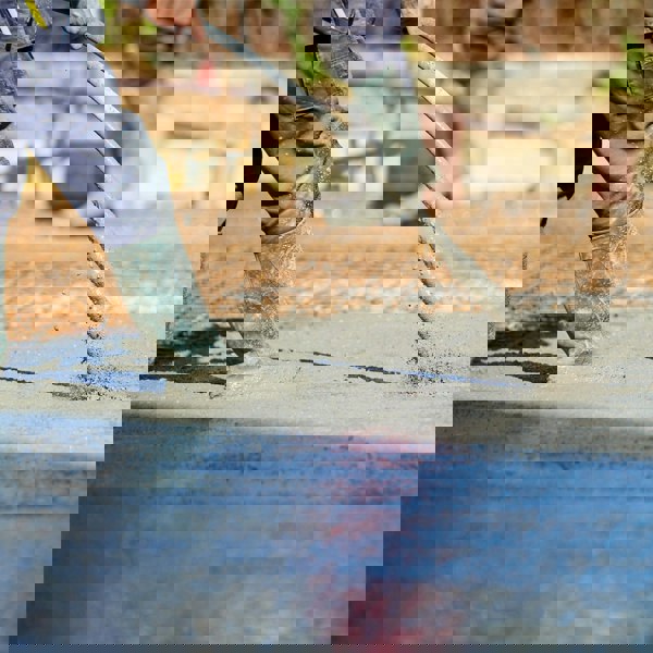 T-Mech Concrete Vibrator in use, smoothing wet concrete surface with a flexible shaft, worker in waterproof boots on site