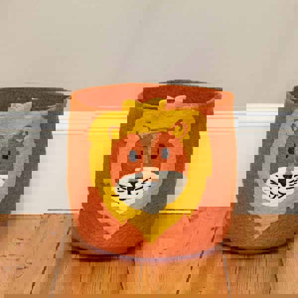 A felt lion storage basket on a wooden floor.