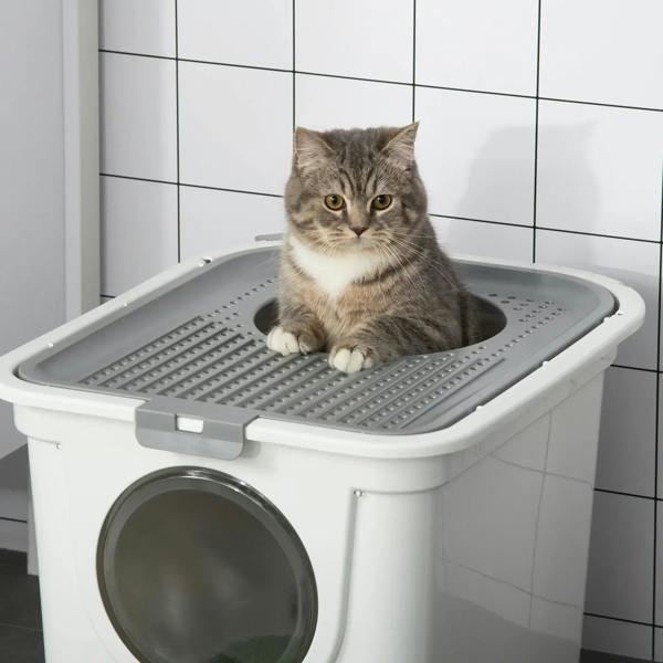 Cat sitting on the grated top tray of a white enclosed litter box