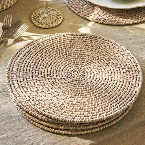 Set of 4 round whitewash rattan placemats styled on a linen tablecloth with glassware.