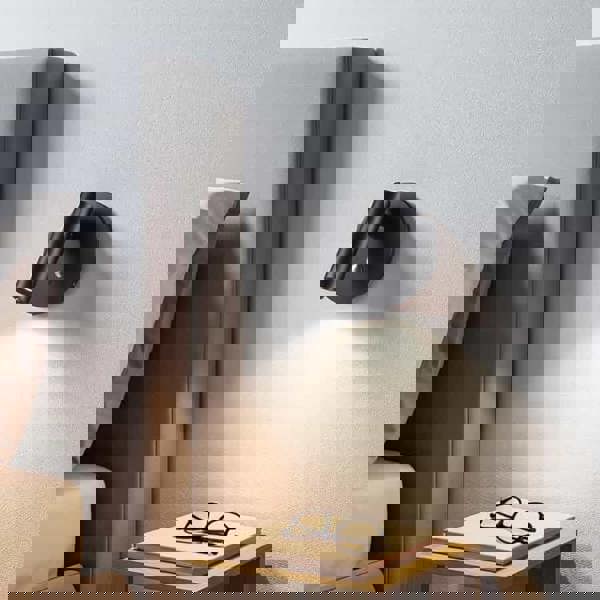 black recessed bed reading light mounted on the wall above a bedside table in a bedroom