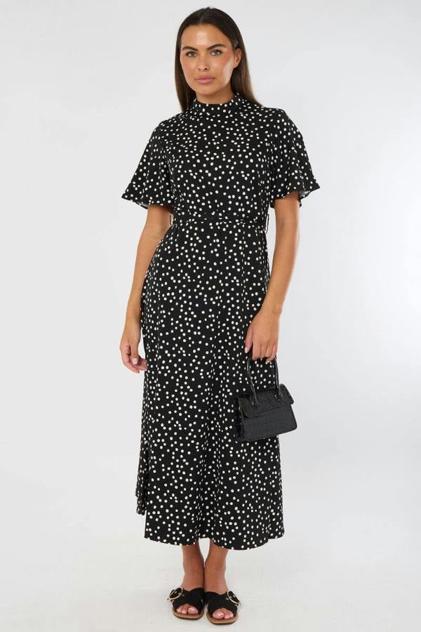 Woman wearing a black dress with white polka dots against a white background
