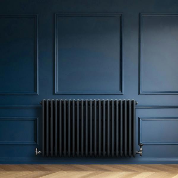 Traditional 4 column radiator in anthracite grey, featuring a sleek, modern design against a deep blue wall and herringbone floor