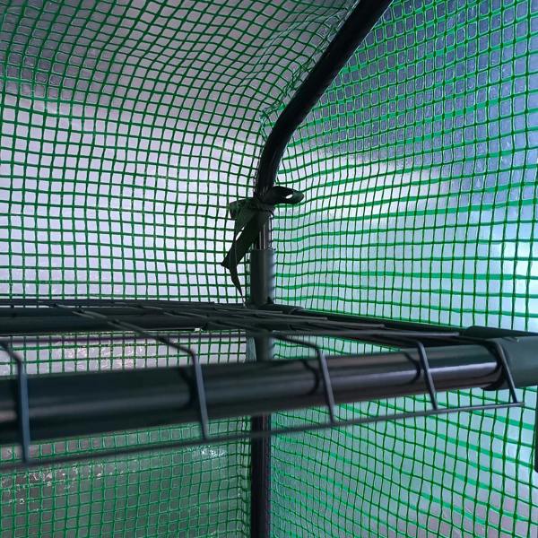 Interior view of dark green greenhouse with black shelf frame and mesh roof