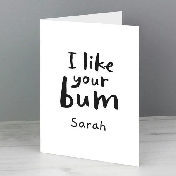 A vertical white card displaying bold black handwritten text that reads I like your bum Sarah against a gray background.