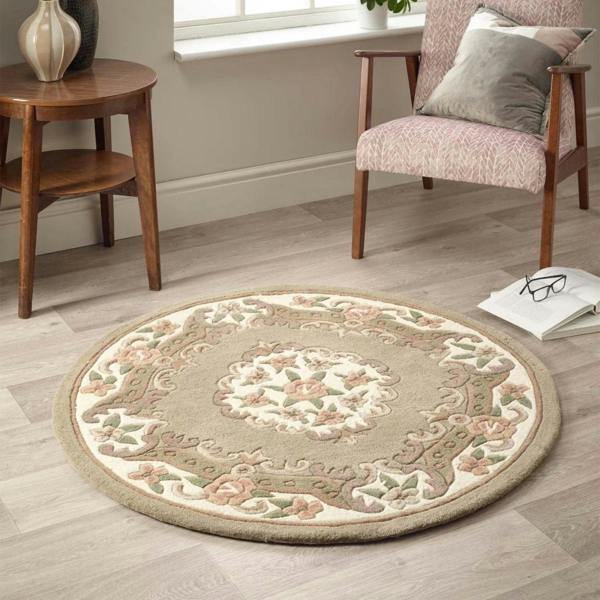 Round decorative rug on a wooden floor with a chair and small table in the background.