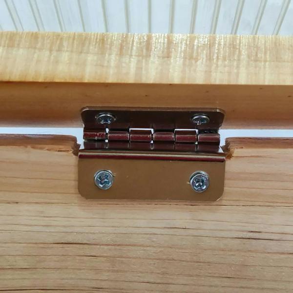 Wooden cold frame greenhouse close-up of metal hinge latch on side rail