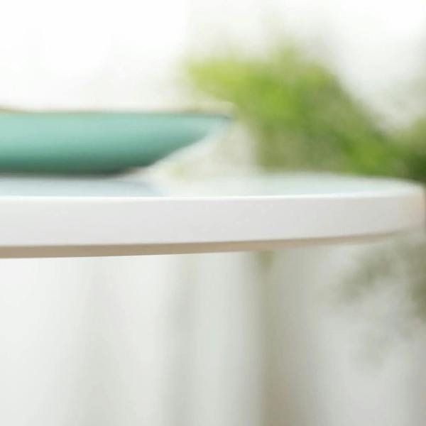 Close-up of the white tabletop edge of a round pedestal dining table