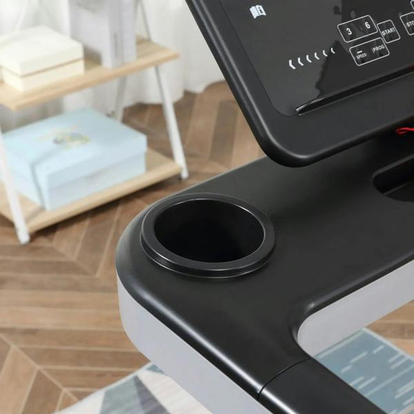 Black treadmill console area with circular cup holder opening and control buttons
