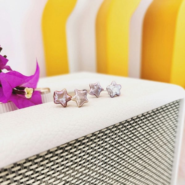 Pink pearl star ear jackets displayed on a speaker with a colourful background.