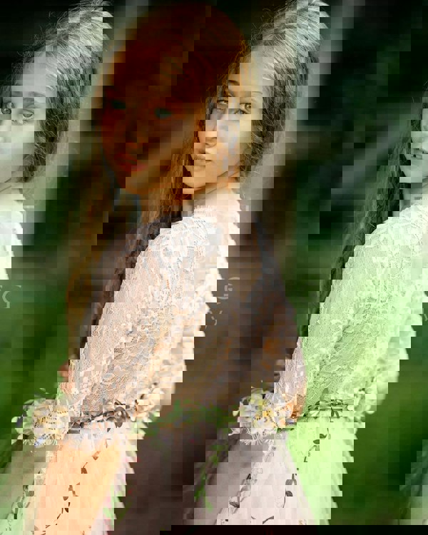 Young girl in a lace dress with floral accents outdoors