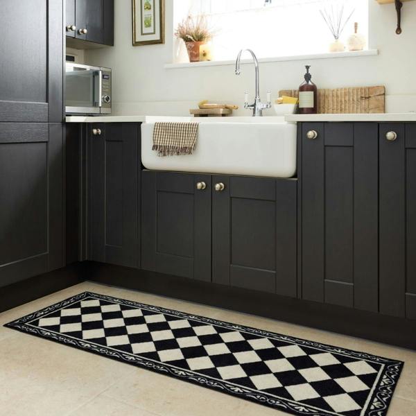 Kitchen with black cabinets, white sink, and a checkered floor mat.