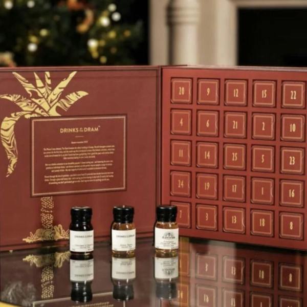 An open premium burgundy and gold spiced rum advent calendar showing 24 numbered doors with three wax-sealed miniature bottles in front.