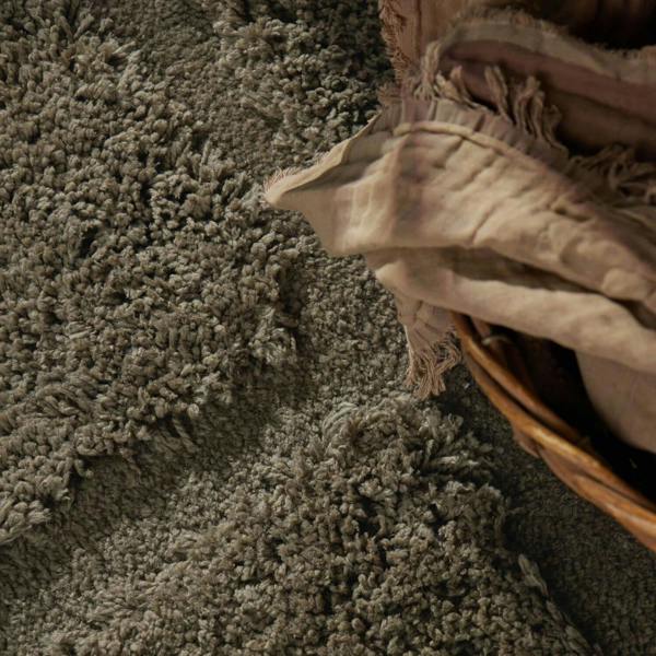 Brown textured rug with a woven basket and folded blanket on top