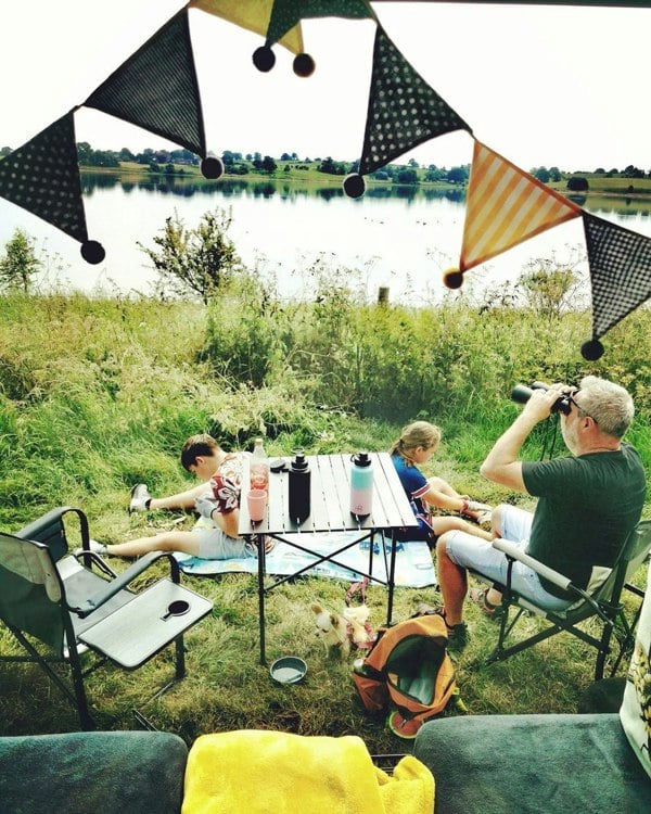 An image of a family using Folding Camp Table from OLPRO near a body of water.