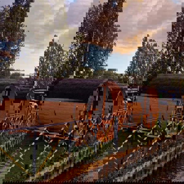 Wooden barrel saunas along a waterway.