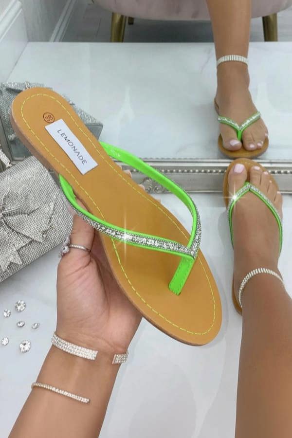 Person holding a sandal with a visible brand label in front of a mirror.